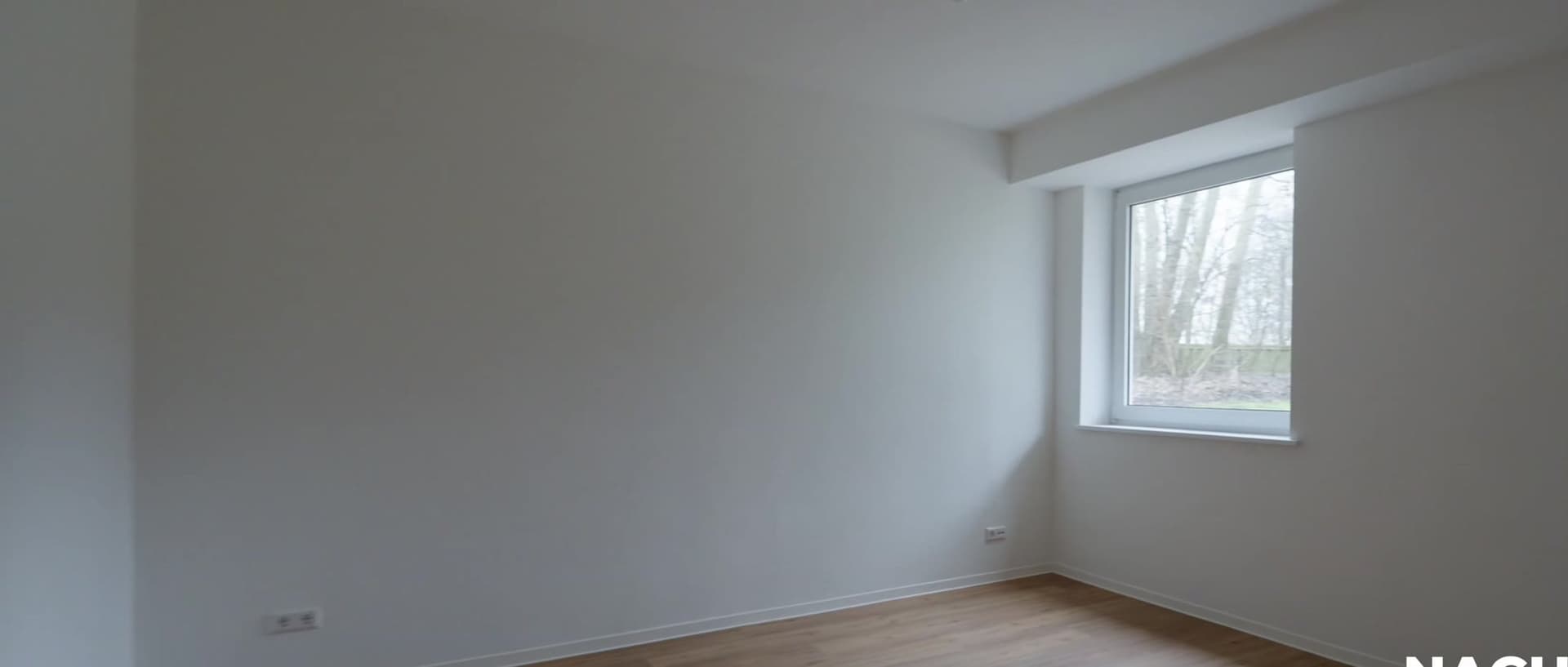 Dasselbe Zimmer nach der Sanierung mit hellen Wänden und Holzboden